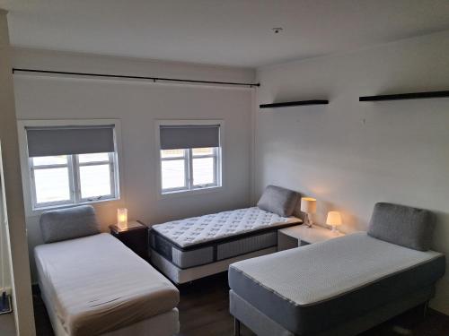a small room with two beds and two windows at KEF QuickStay Apartments in Keflavík