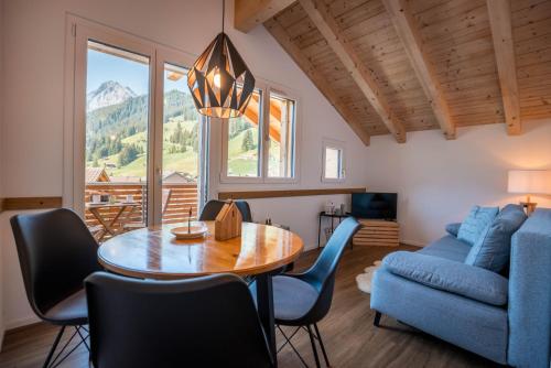 a living room with a table and a blue couch at Chuenislodge3 neu&stilvoll, 2Balkone, echtes Bijou mit top-Aussicht in Adelboden
