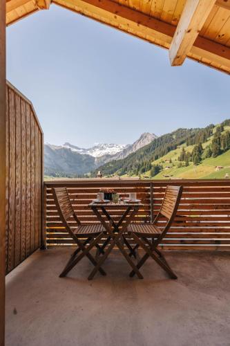 a table and two chairs on a balcony with mountains at Chuenislodge3 neu&stilvoll, 2Balkone, echtes Bijou mit top-Aussicht in Adelboden
