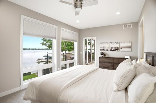 a white bedroom with a large bed and large windows at Lakefront Luxury in Mound