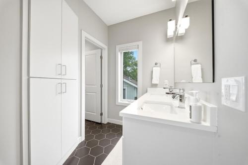 a white bathroom with a sink and a mirror at Lakefront Luxury in Mound