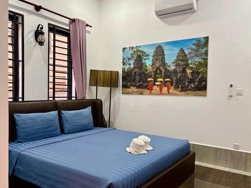 a bedroom with a bed with blue sheets and a painting on the wall at Lotus Haven Villa in Siem Reap