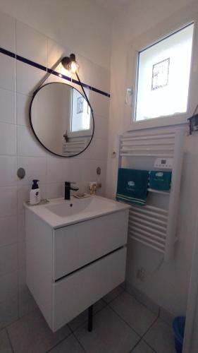 a white bathroom with a sink and a mirror at L'écrin d'Ar Prajou in Plouénan