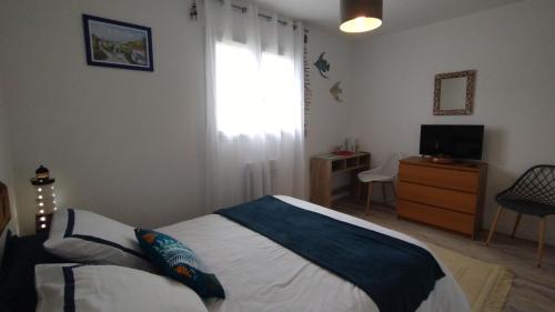 a bedroom with a bed and a television and a window at L'écrin d'Ar Prajou in Plouénan