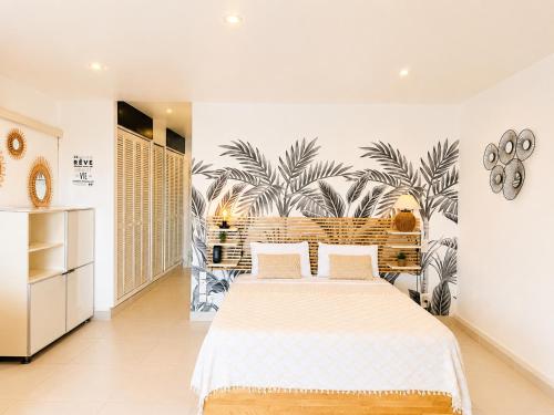 a bedroom with a large bed and a palm mural at Studio ALIZEA in Saint Martin