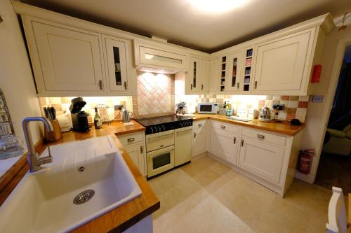 a kitchen with white cabinets and a sink at Rose Cottage in Buxton