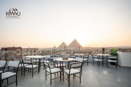 a room with tables and chairs with pyramids in the background at Riwaq Pyramids View Inn & Rooftop in Cairo