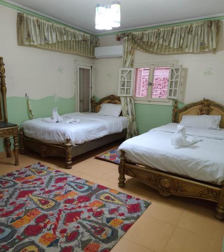 a bedroom with two beds and a rug at Sunset Mirage House in Giza