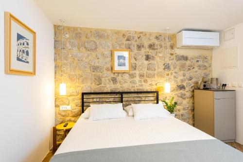 a bedroom with a large bed and a stone wall at Villa Four Winds II in Dubrovnik