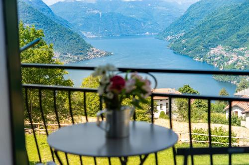 a table with a vase of flowers on a balcony overlooking a lake at Incanto del Lago Country House in Faggeto Lario 