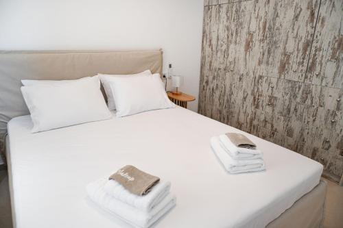 a white bed with towels and a phone on it at Mandrakia Living House in Mandrakia