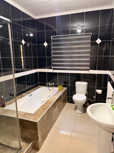 a bathroom with a tub and a toilet and a sink at The Marina Suite in Mbabane