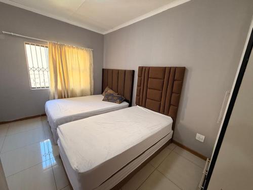 two beds in a small room with a window at The Marina Suite in Mbabane