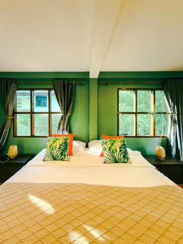 a bedroom with a large bed with two windows at Nong Thale Garden in Ban Khao Klom