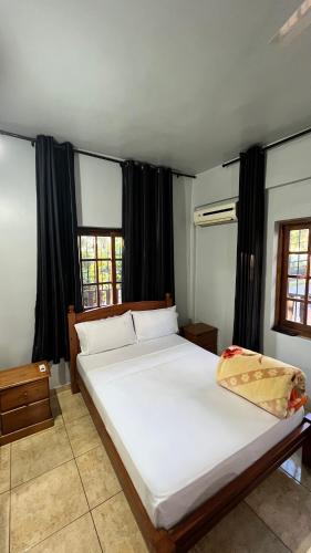 a bedroom with a large white bed with black curtains at Hostel Peter Pan in Puerto Iguazú