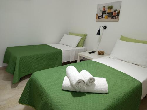 two beds in a room with green sheets and towels at Casa Melf in Terrasini