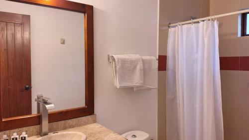 a bathroom with a white shower curtain and a mirror at HOTEL XIADANI Restaurante, Temazcal & Spa in Tlaxcala de Xicohténcatl