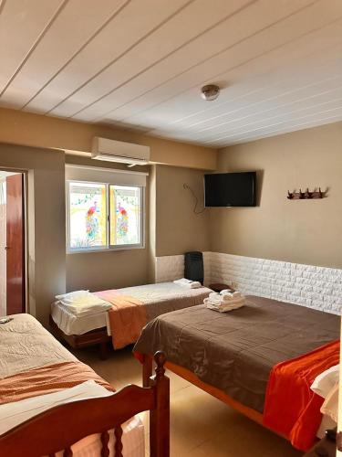 a room with two beds and a tv on the wall at Hotel America in Victoria