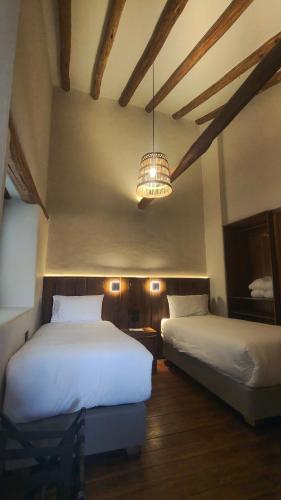 a bedroom with two beds and a chandelier at El Balcón in Cusco