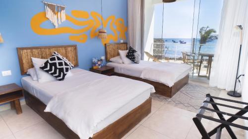 two beds in a room with a view of the ocean at qema Mancora in Máncora