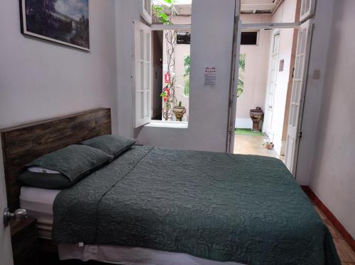 a bedroom with a bed with a green comforter and a window at Santa Beatriz in Lima