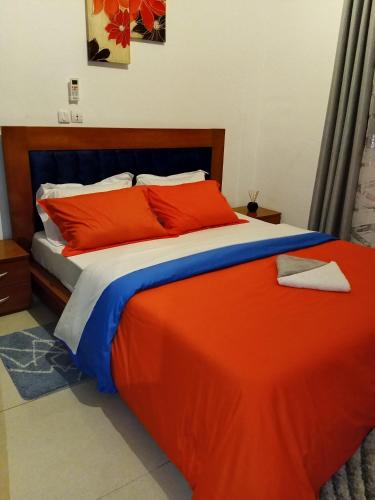 a bedroom with a bed with orange and blue sheets at Eva Apparts "situé à Kotto Baden Baden" - PARKING CAMERA BALCON WIFI CLIM CONFORT in Douala