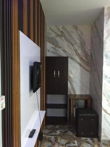 a room with a tv and a desk with a chair at The Maison Lodge in Ijegun