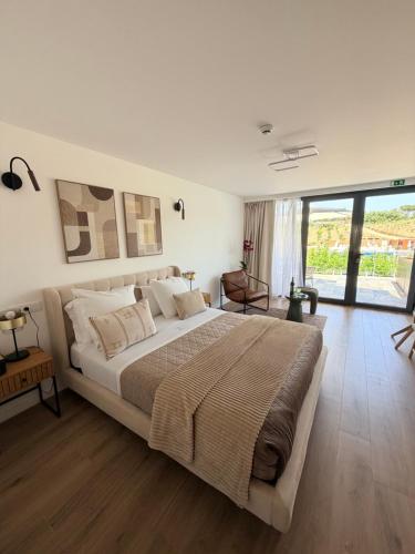 a bedroom with a large bed and a large window at Zambujal Suites in Sesimbra