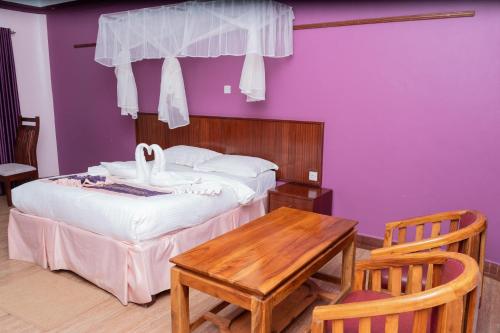 a bedroom with a bed and a table and purple walls at Destination Resort Centre in Gikuu