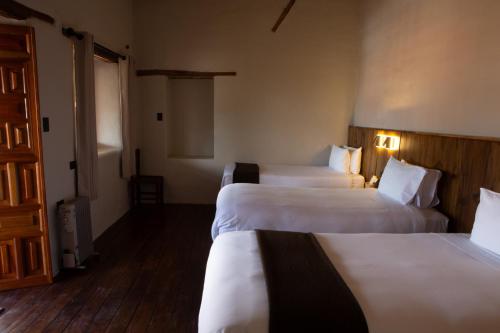 a hotel room with three beds with white sheets at El Balcón in Cusco