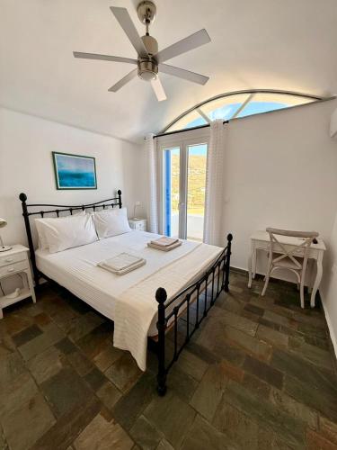 a bedroom with a large bed with a ceiling fan at Aegean Big Blue -Rosalie Home in Tinos
