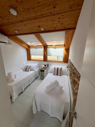 two beds in a room with wooden ceilings at Mar De Pedra in Cangas de Morrazo