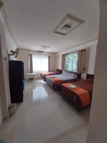 ein Hotelzimmer mit drei Betten und einem Fenster in der Unterkunft L J in Trinidad