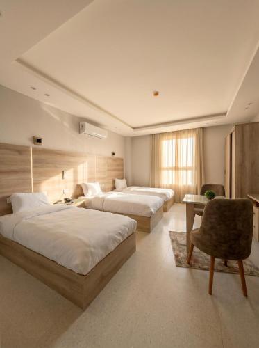a hotel room with two beds and a chair at Elite hotel in Sheikh Zayed