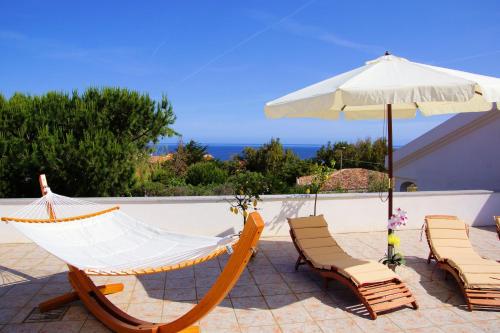 a hammock and chairs and an umbrella on a patio at Sa Fiorida Appartamenti in Valledoria