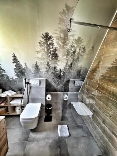 a bathroom with a toilet and a painting of trees at Jahorina Luxury Chalets in Jahorina