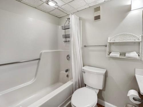 a white bathroom with a toilet and a bath tub at Mountain Green Resort in Killington Village