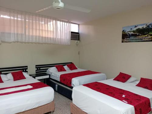 a bedroom with two beds with red sheets at Hotel Resident Piura in Piura