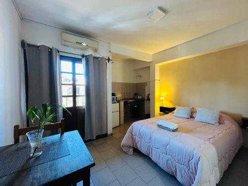 a bedroom with a bed and a table and a kitchen at Pequeño Monoambiente céntrico 1E in Puerto Iguazú