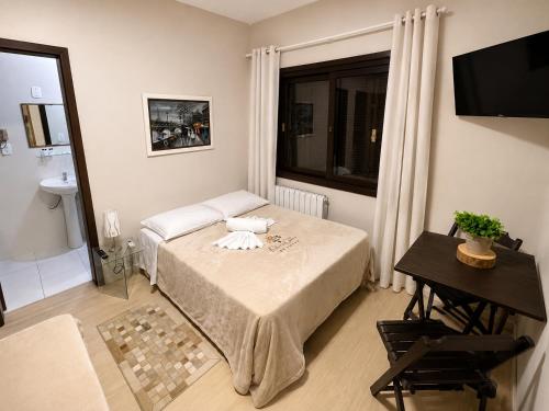 a small room with a bed and a window at Pousada Folhas de Outono in Canela