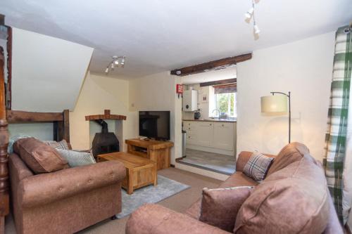 a living room with two couches and a kitchen at The Stables - Old Mill Cottages in Ilfracombe