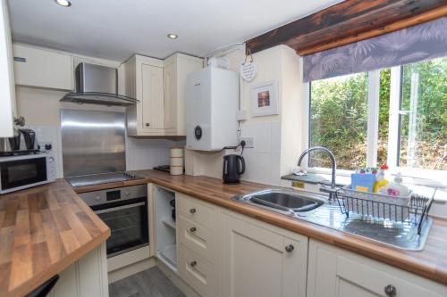a kitchen with white cabinets and a sink at The Stables - Old Mill Cottages in Ilfracombe