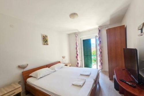 a bedroom with a bed and a tv and a window at Apartmani Franceska in Bol