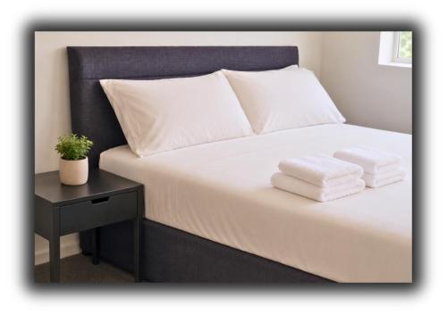 a bed with white sheets and two towels on it at The Red Lounge Rooms in Liverpool