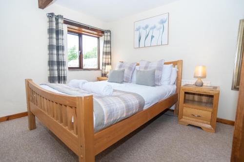a bedroom with a wooden bed and a window at Treetop View - Old Mill Cottages in Ilfracombe