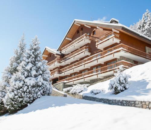 a building covered in snow with trees in front at Appartement rénové à Méribel Centre, avec Balcon et à 5 minutes des pistes et du centre in Méribel