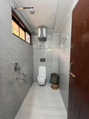 a small bathroom with a toilet and a window at Laxman Homestay in Sarāhan