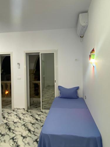 a bedroom with a blue bed in a white room at Villa pamplemousse in Banī ‘Aţāʼ