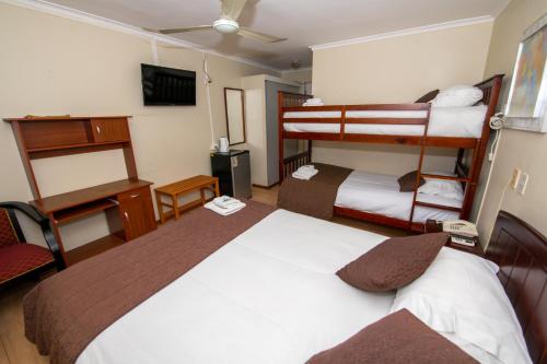 a hotel room with two bunk beds and a television at Hotel San Francisco De la Selva in Copiapó