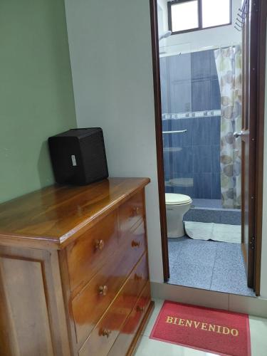 a bathroom with a wooden dresser with a television on top at Casa Puka in Puerto Baquerizo Moreno